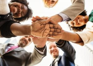Group of people in circle with hands of top of each other